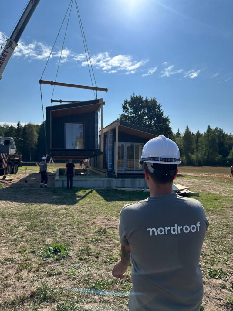 A sustainably built home with a man standing nearby, showcasing Nordroof's commitment to the environment and community.